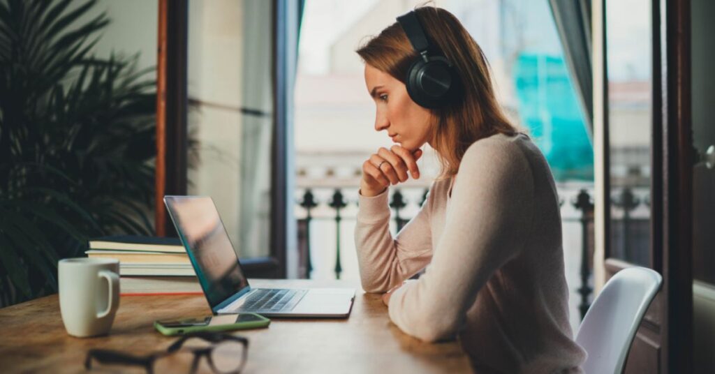 Women wearing headphones watching a video on a laptop